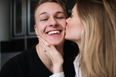 Mutlu adam gülümserken kadın yanaktan öpüyor ve kafede oturup birlikte vakit geçirirken aşka sarılıyor.