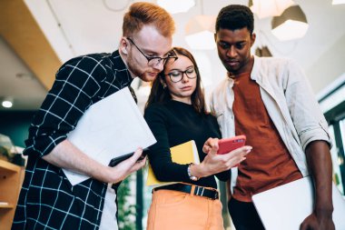 Ofis koridorunda durup dinlenirken sosyal medyada akıllı telefonları karıştıran kadın ve erkeklerin düşük açısı.