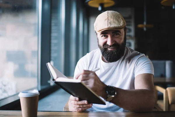 Gülümseyen Şapkalı Olgun Sakallı Erkek Yazarın Portresi Kafenin Içinde Uzaktan — Stok fotoğraf