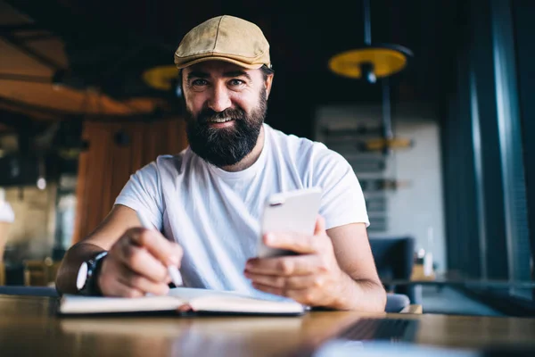 Hombre Barbudo Feliz Sentado Cafetería Navegando Por Teléfono Celular Con — Foto de Stock