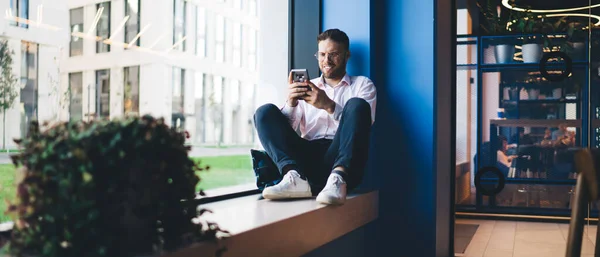 평상복과 안경을 긍정적 사업가가 직장에서 가까이에 일하는 스마트폰으로 메시지를 — 스톡 사진