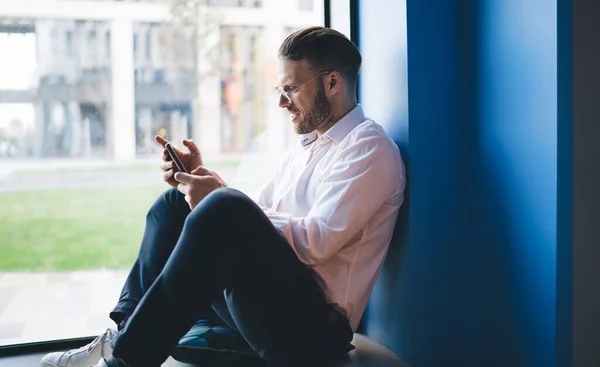 Gündelik Beyaz Gömlekli Pencerenin Yanında Oturan Akıllı Telefon Kullanırken Sosyal — Stok fotoğraf