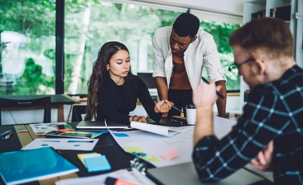 Young team of creative successful business people in casual clothes working together with papers and sharing ideas about startup project