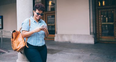 Sırt çantası okuyan neşeli İspanyol öğrenci, şehir merkezinde ayakta duran üniversite ders programı hakkında e-posta aldı. Cep telefonu uygulaması üzerinden mutlu kadın turist izleme ağı konumu.