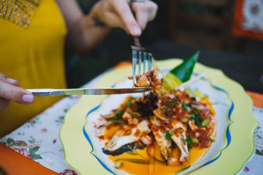 Yazlık kıyafetleri içinde tanınmayan, soslu ve sebzeli lezzetli deniz ürünlerinin tadını çıkaran, restoranda masada oturan, tanınmamış bir kadın.