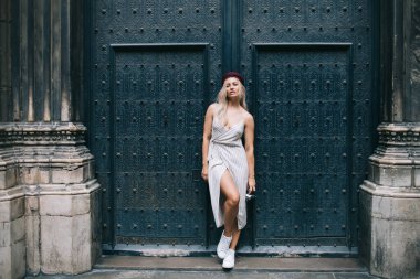 Tarihi merkezde şık bir şekilde poz veren güzel beyaz mankenin tam boy portresi, gezi sırasında kameraya bakan muhteşem kıyafetli hippi kız.