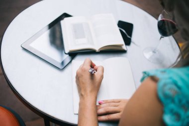 Edebiyat kitabından öğrenme sırasında ders kitabına not yazan kız öğrencinin kırpılmış resmi, masaüstündeki sınav hazırlığı için seçici odak noktası