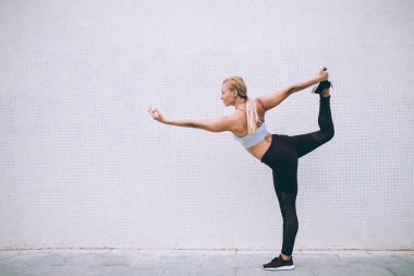 Eşofmanlı enerjik, ince kadın sabahları yoga egzersizleri sırasında Warrior 1 yapıyor. Kadın jimnastikçi, reklam alanında fotokopi alanıyla fiziksel dinlenme süresince virabhadrasana 'nın tadını çıkarıyor.