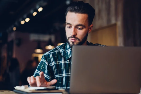 Focused Bearded Male Freelancer Checkered Shirt Using Smartphone Calculating While — Stock Photo, Image