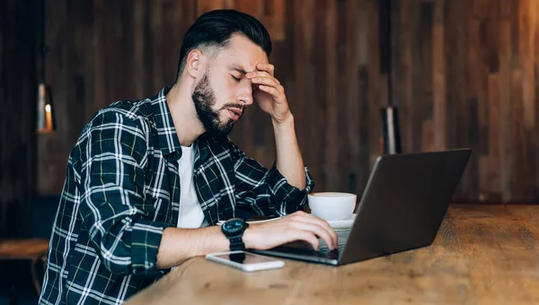 穿着休闲装 闭着眼睛 在笔记本电脑前喝咖啡 在自助餐厅喝咖啡的沮丧男生的侧视图 — 图库照片