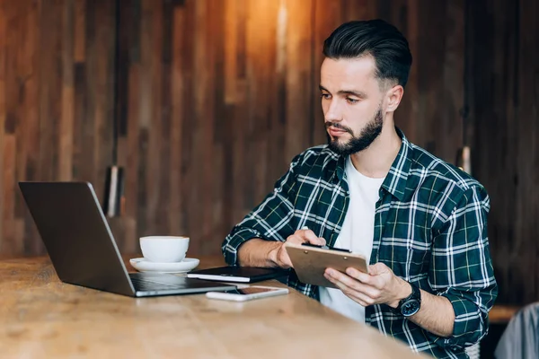 Geconcentreerde Jongeman Met Baard Stijlvol Kapsel Schrijven Informatie Klembord Tijdens — Stockfoto