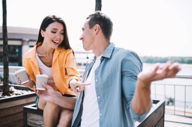 Etnik bayanların tişörtünü göstererek gülmeleri erkek arkadaş şakaları dinlemeleri birlikte eğlenmeleri, kahve içmeleri ve şehrin deniz kenarında dinlenmeleri.