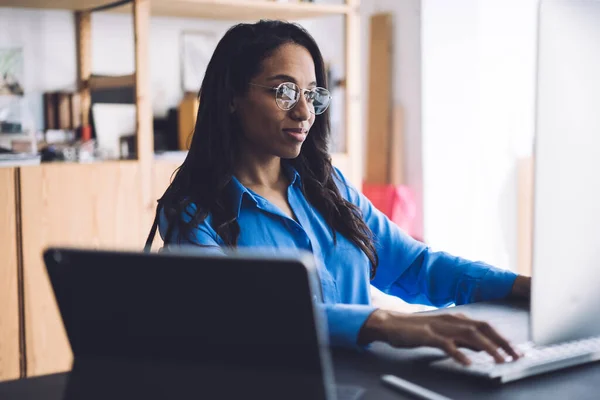 Fornøyd Afroamerikansk Kvinne Sitter Ved Skrivebordet Med Datamaskin Laptop Ser – stockfoto