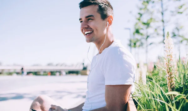 Güneşli havalarda sırtüstü sırtüstü parka oturmuş sırtüstü oturmuş sırtüstü sırtüstü sırtüstü gülümseyen genç bir erkek.