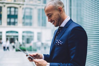 Neşeli Kafkasyalı eğitimci, şehir merkezindeki 4G kablosuz bağlantıya bağlı modern dokunma rampasında çevrimiçi bilgi arıyor, başarılı iş adamı internet sitesi dijital phablet