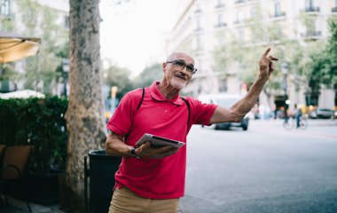 Polo tişörtlü ve gözlüklü, gülen sakallı bir erkek emekli. Şehir merkezinde yürüdükten sonra tablet dolu taksi kullanıyor.