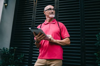 İnce sakallı, gözlüklü, gözlüklü, gözlüklü, internette gezinen ve şehirde tablet kullanan son sınıf öğrencisi.