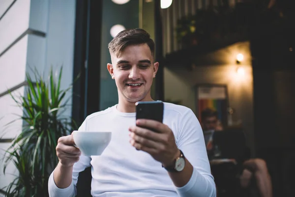Freelancer Masculino Sonriente Con Atuendo Casual Navegando Por Smartphone Mientras —  Fotos de Stock