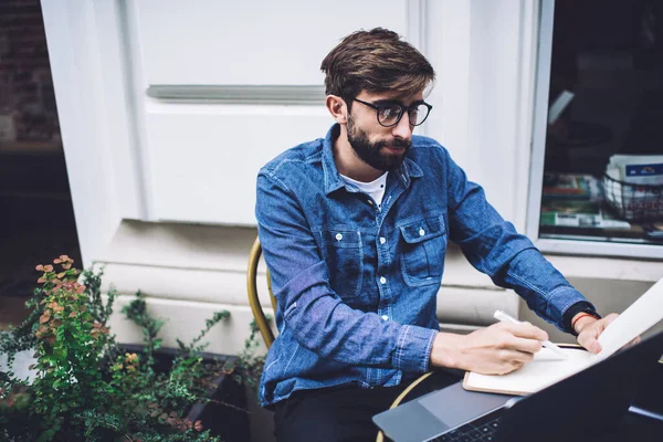 Adulto Focado Freelancer Masculino Tomando Papel Escrevendo Agenda Enquanto Sentado — Fotografia de Stock