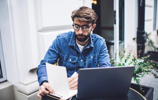 Focalizzato Barbuto Giovane Uomo Abiti Casual Occhiali Prendere Appunti Navigazione — Foto Stock