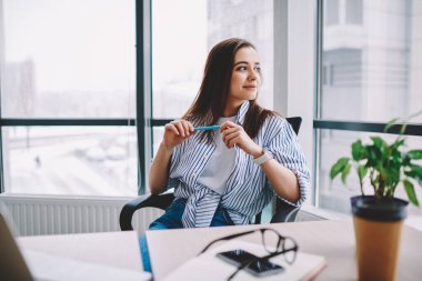 Düşünceli, serbest çalışan, masa başında elinde kırpılmış netbook 'la oturan ve gazetecilik fikirlerini düşünürken başka yere bakan düşünceli, rahat giyinen, hayal kuran düşünceli bir kadın.