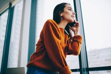 Gündelik giyinmiş 20 'li yaşlardaki hippi kız 4G kablosuz telefon görüşmesi yapmak için beyaz kadın telefon uygulaması kullanıyor ve müşteri hizmetlerine danışmanlık yapıyor.