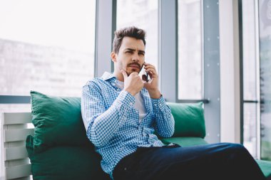 Ciddi kafası karışmış bir adam, iş görüşmesi için danışman akıllı telefon konuşması yapıyor. Beyaz, rahat giyinen bir erkek. Kapalı alandaki cep telefonu iletişimi sırasında kafası karışmış.