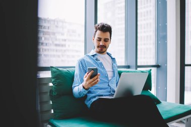 Beyaz tenli hippi adam bluetooth bağlantısını kullanarak cep telefonu ve dizüstü bilgisayarla bilgi paylaşıyor. Akıllı telefondaki uygulamadan gelen mesajları okuyabilen yetenekli bir erkek.