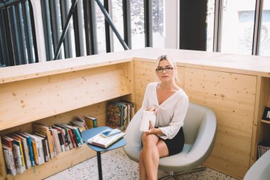 Görme koruması için optik gözlüklü çekici kadın gazetecinin portresi edebiyatın en çok satan kitaplarını elinde tutuyor ve kameraya bakıyor, zeki kadın bilgilendirici araştırmalar için zaman harcıyor.