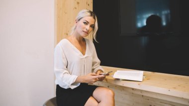 Edebiyat kitaplarında öğrenme ve bilgilendirici araştırmalar için modern cep telefonu cihazında 4G kablosuz internet bağlantısı kullanan yetişkin öğrenci portresi, cep telefonu pozu veren kadın