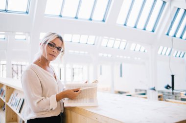 Klasik gözlüklü çekici yetişkin öğrencinin yarım boy portresi üniversitede öğrenim ve öğrenim sürecinde kameraya bakarak göz düzeltmesi sağlar, gözlüklü beyaz kadın