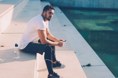 Elektronik stereo ekipmanları dinleyen düşünceli erkek vücut geliştirici idman üzerinde kafa yoran kişisel antrenörden sesli mesaj aldı.