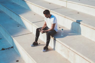 Kaslı koşucu, sosyal takipçilerle mesajlaşmak için web günlüğünden sağlıklı yaşam tarzı hakkında alıştırma yapıyor. İyi görünümlü bir adam, arama çevrimiçi eğitimi için cep telefonunda 4G kablosuz kullanıyor.