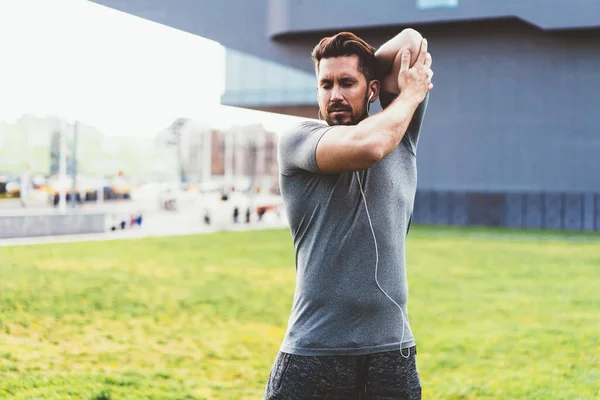 Caucasian Athletic Runner Stretching Arms Muscles Doing Cardio Workout Listening — Stock Photo, Image