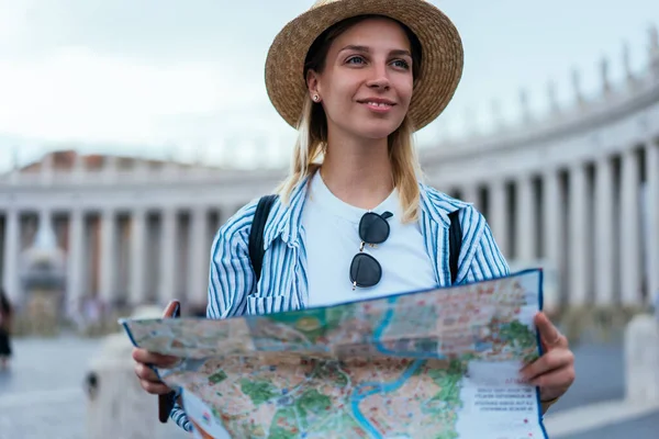 Charming female dressed in casual wear holding touristic map for searching route for sightseeing tour, smiling Caucasian traveler 20 year old enjoying Italian vacations for visiting Vatican city