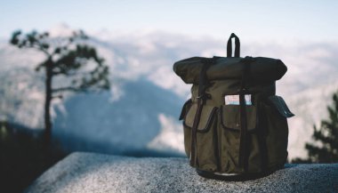 Yosemite Ulusal Parkı 'ndaki dağlık arazide kayaların üzerinde duran yalnız turist sırt çantasının heybetli manzarası.