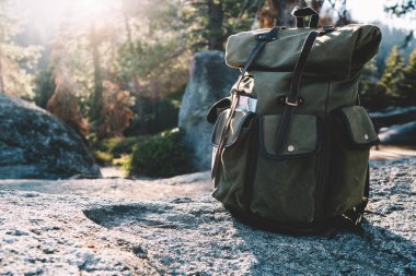 Güneşli bir günde Amerika 'daki Yosemite Ulusal Parkı' nda taşlı bir zeminde yalnız bırakılan yeşil turistik yürüyüşçü çantası.