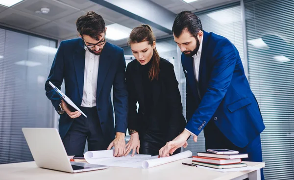 Group of experienced architects discussing main problems of project making creative solutions, professional male and female colleagues planning design sketch during collaborative brainstorming