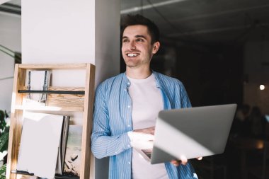 Neşeli beyaz erkek metin yazarı dizüstü bilgisayarın güncellenmesini beklerken gülümsüyor. Mutlu hipster adam modern netbook bilgisayarından online alışveriş yaparken kendini iyi hissediyor.