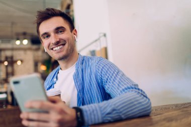 Eğlenceli müzik dinlemek için cep telefonu kullanan komik beyaz adamın yarım boy portresi. Bluetooth kulaklıklı neşeli bir erkek milenyum. Müzik kayıtlarının keyfini çıkarıyor.