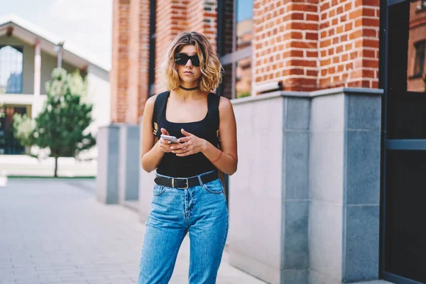 Jovem Fêmea Moda Jeans Óculos Sol Navegando Smartphone Olhando Para — Fotografia de Stock