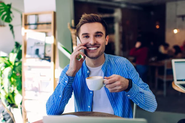 Ung Lykkelig Mann Blå Skjorte Som Snakker Mobiltelefon Drikker Kaffe – stockfoto