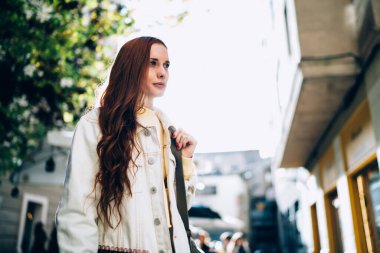 Güneşli bir günde Barcelona Caddesi 'nin bulanık arka planında duran uzun kızıl saçlı güzel bir kadın.