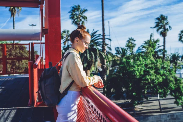 観光バックパックを持つ瞑想的な女性旅行者のサイドビュースペインの通り 魅力的な白人のヒップスター女の子で都市の設定で立っている新しい都市を探索するための目的地の方法について熟考 — ストック写真