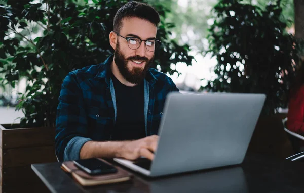 Konzentrierter Bärtiger Mann Mit Brille Und Lässigem Outfit Sitzt Holztisch — Stockfoto