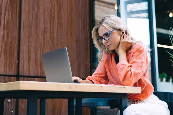 Концентрированная Молодая Женщина Фрилансер Повседневной Одежде Очках Думая Используя Ноутбук — стоковое фото