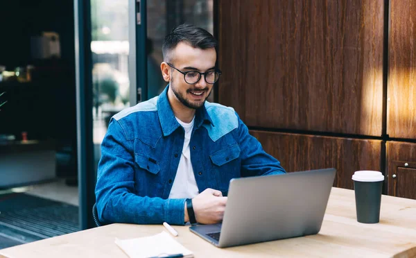 Bearded Male Student Wearing Jean Jacket Using Laptop Smiling While — Stock Photo, Image