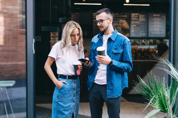 Young Couple Cups Coffee Standing Cafe While Man Showing Mobile — Stock Photo, Image