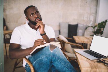 Ciddi bir düş gören koyu tenli hippi, iş yerinin yanında oturup yazı yazma fikri üzerine kafa yoruyor. Bilgisayar maketi, kendine güvenen zeki erkek gazeteci, notlar yazıyor.