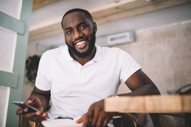 Yakışıklı, koyu tenli, 20 'li yaşlardaki hippi, marka adı ya da etiketi için fotokopi alanı olan, akıllı telefon kullanan, mutlu Afro-Amerikan sakallı adam. Ofisteki cep telefonuyla binlerce yıllık postaları kontrol ediyor.